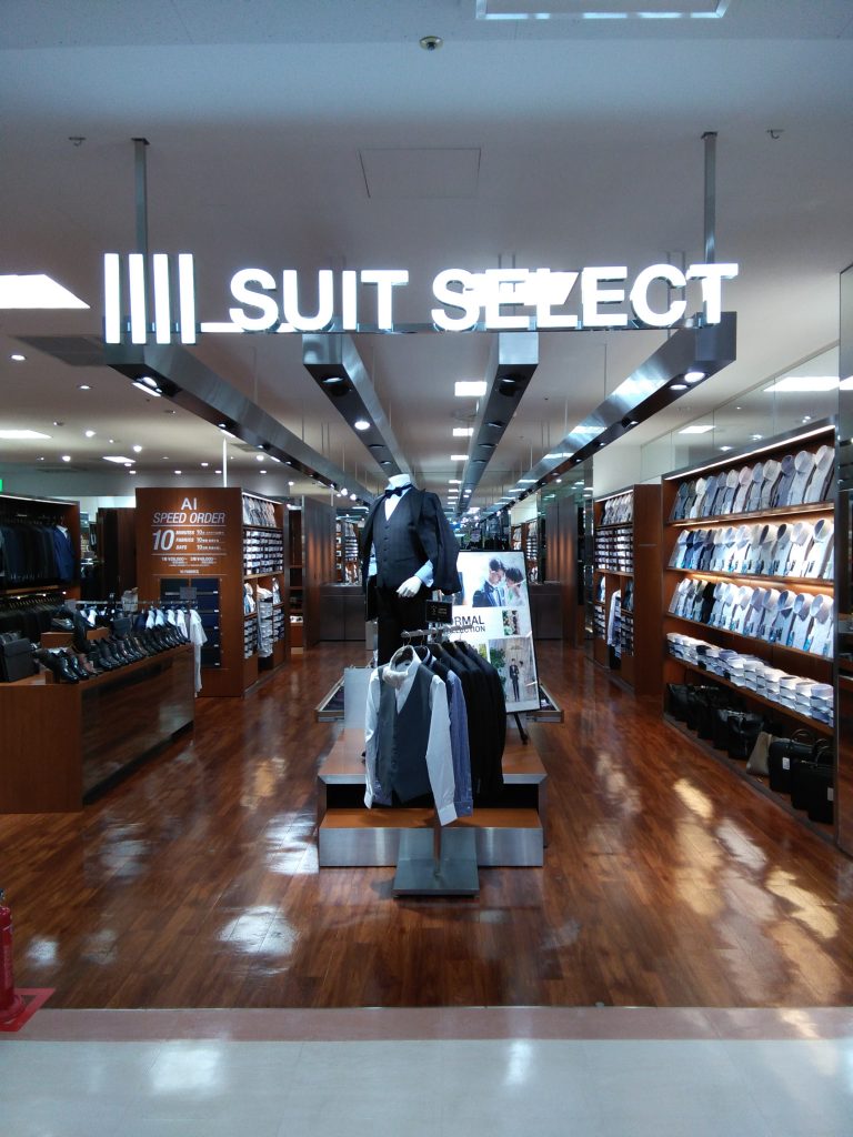スーツセレクトゆめタウンはません店頭。
店頭にはブラックスーツを着用したリアルマネキンと、ジレ(ベスト)がラックに演出されています。