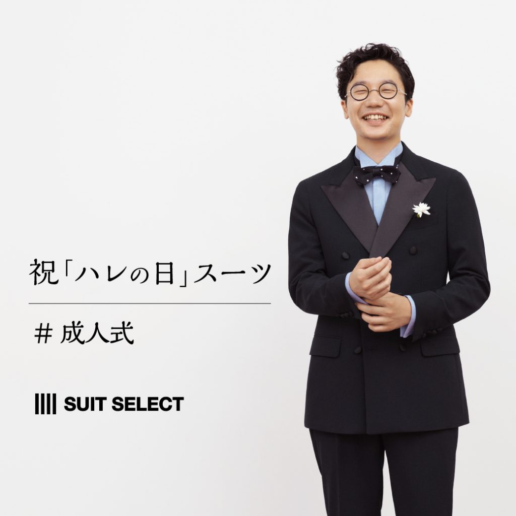 前原さんが、左手で右手のカフスを正すようなしぐさで、こちらを見て微笑んでいる。腰から上の画像。
服装は、ブラックのダブルのスーツスタイル。
淡いブルー系のシャツ、ニット素材のボウタイ（ホワイトドット柄）を合わせている。胸元には白い花。
背景は白。
スーツセレクトの横型ロゴ記載があるポスター画像。
文言は”祝「ハレの日」スーツ”。
その下に＃成人式と記載されている。