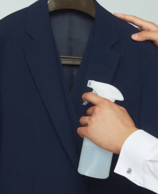 スーツに霧吹きスプレーをしている様子の写真
